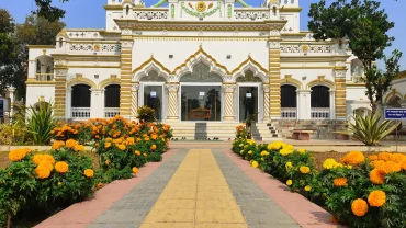 a yellow and white building with flowers in front of it